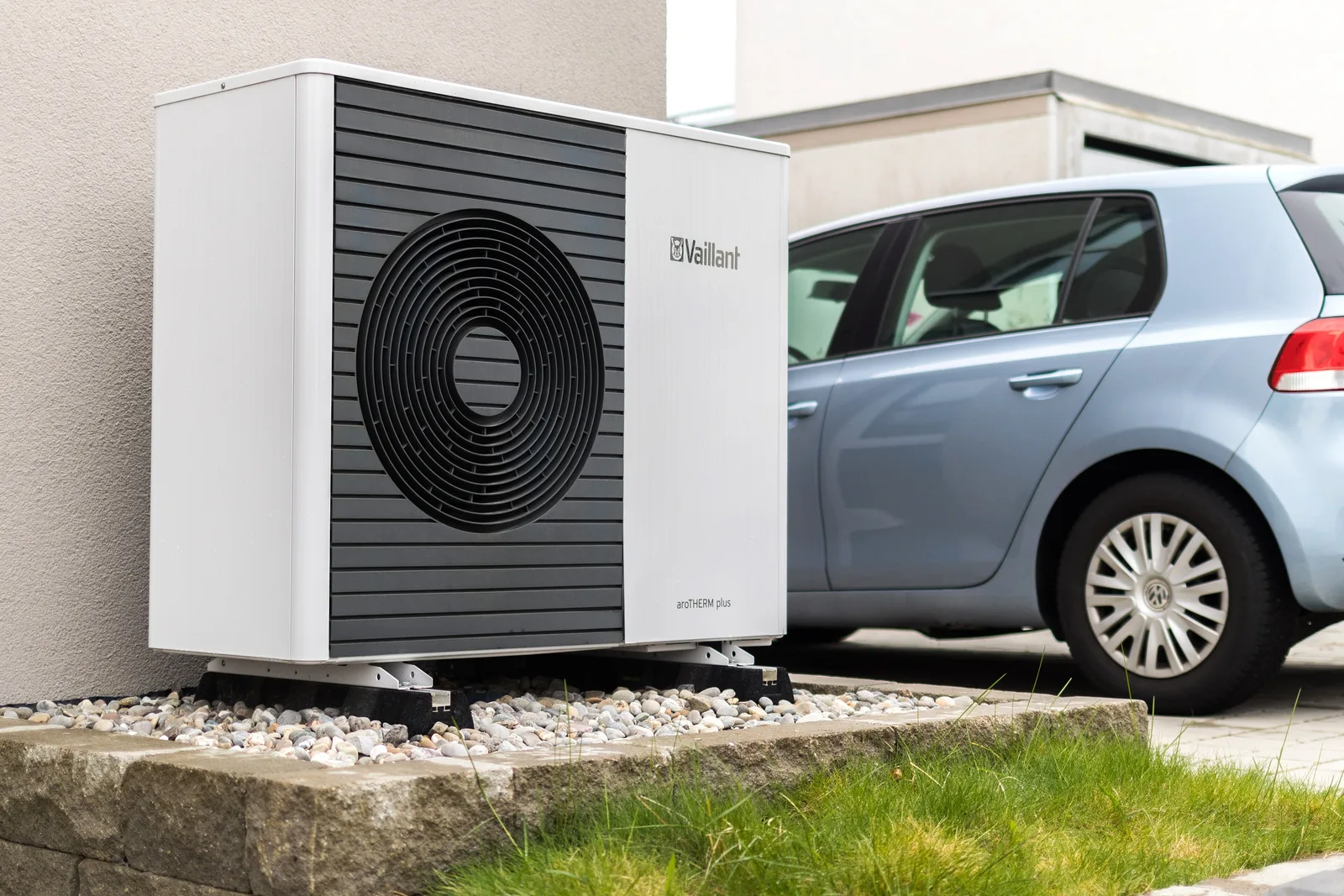 Unité extérieure de pompe à chaleur air-eau posée sur des supports antivibratiles au pied d'une façade