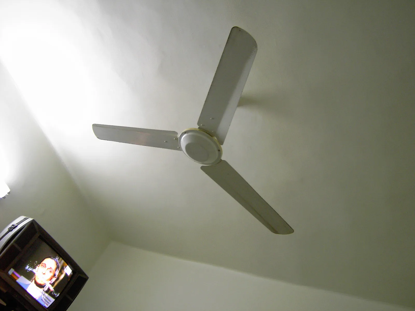 Brasseur d'air à trois pales blanches fixé au plafond d'une chambre