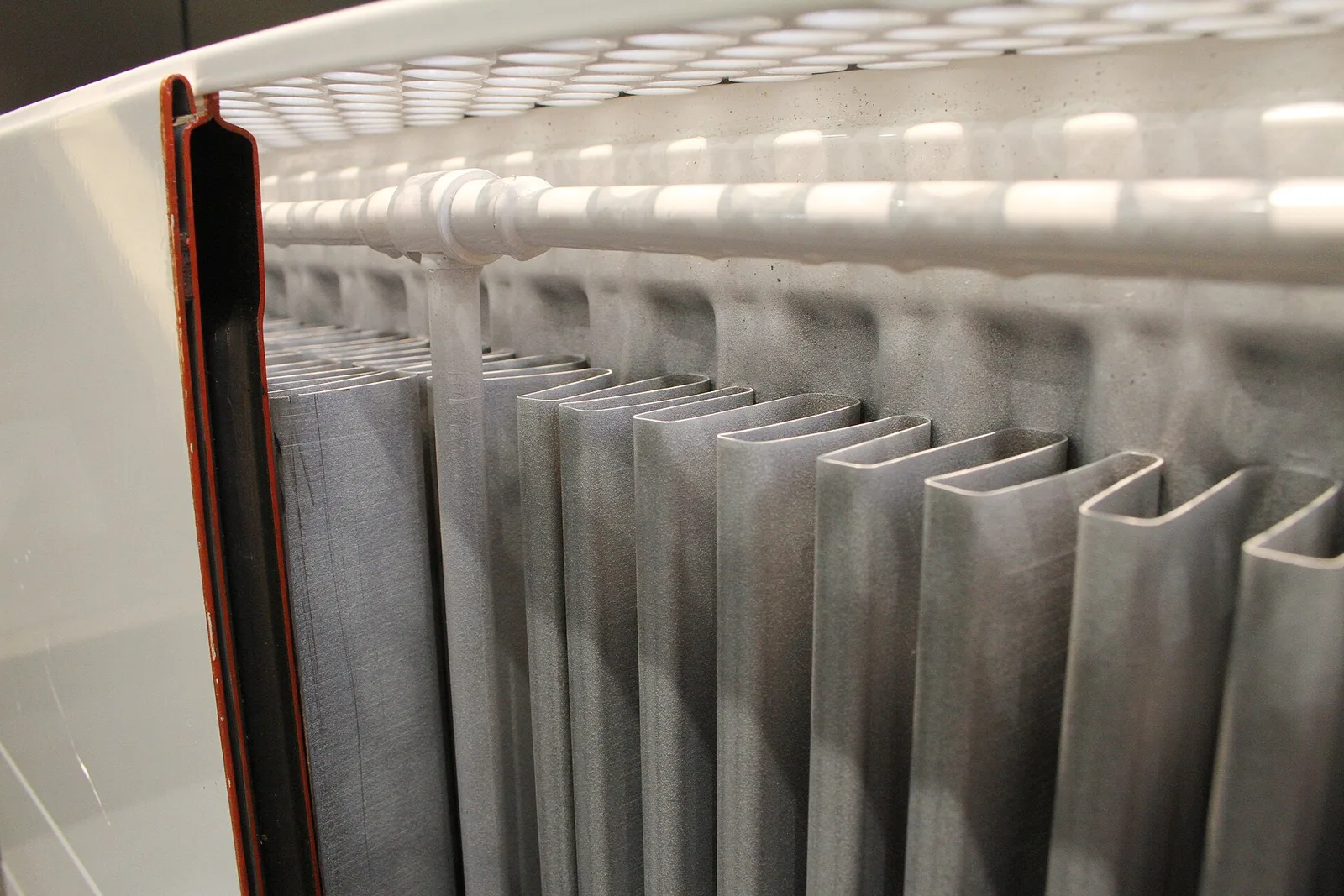 Radiateur à panneaux découpé montrant l'intérieur : canaux verticaux et ailettes de convection où circule l'eau du chauffage central