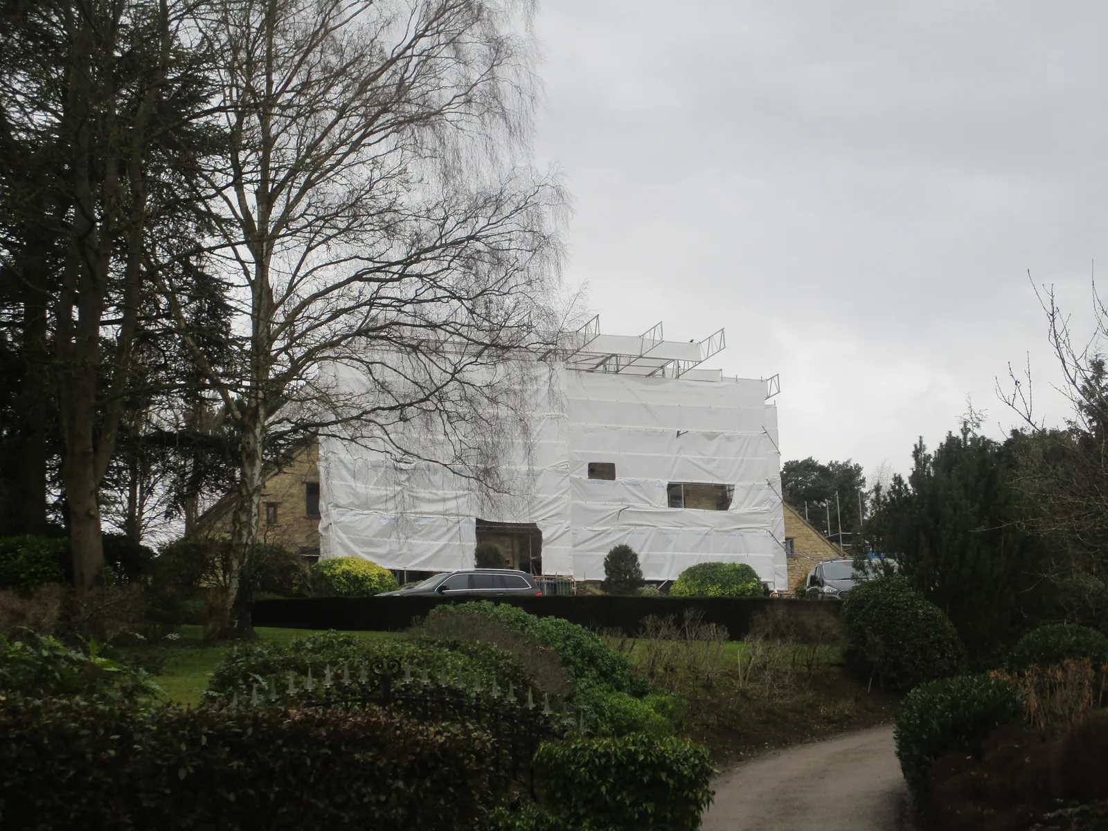 Maison en pierre sous bâche blanche et échafaudage pendant des travaux de rénovation