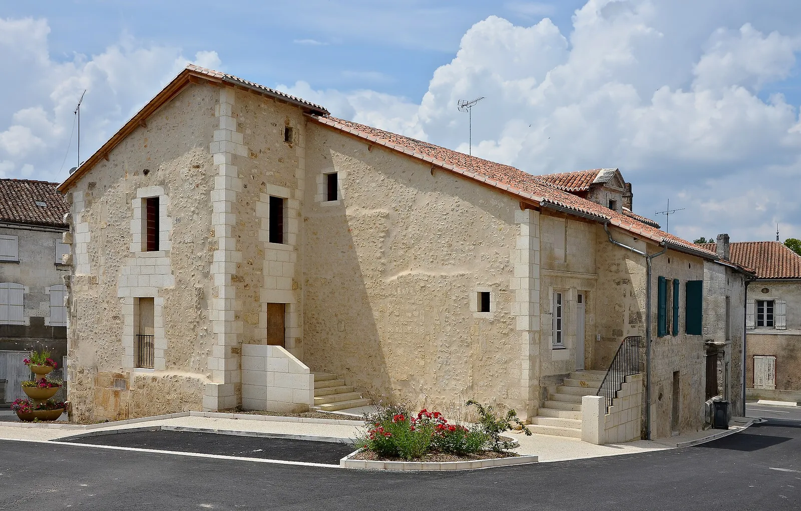 Maison ancienne en pierre aux enduits clairs et à toit de tuiles, rénovée, dans une rue de village en Dordogne
