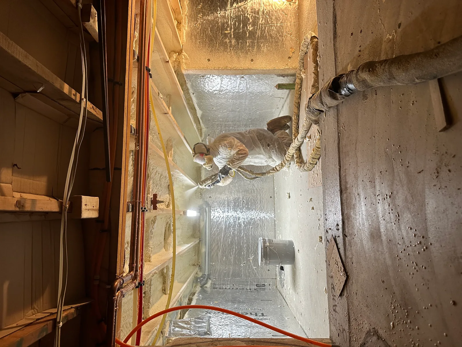 Technicien appliquant de la mousse isolante projetée dans un vide sanitaire