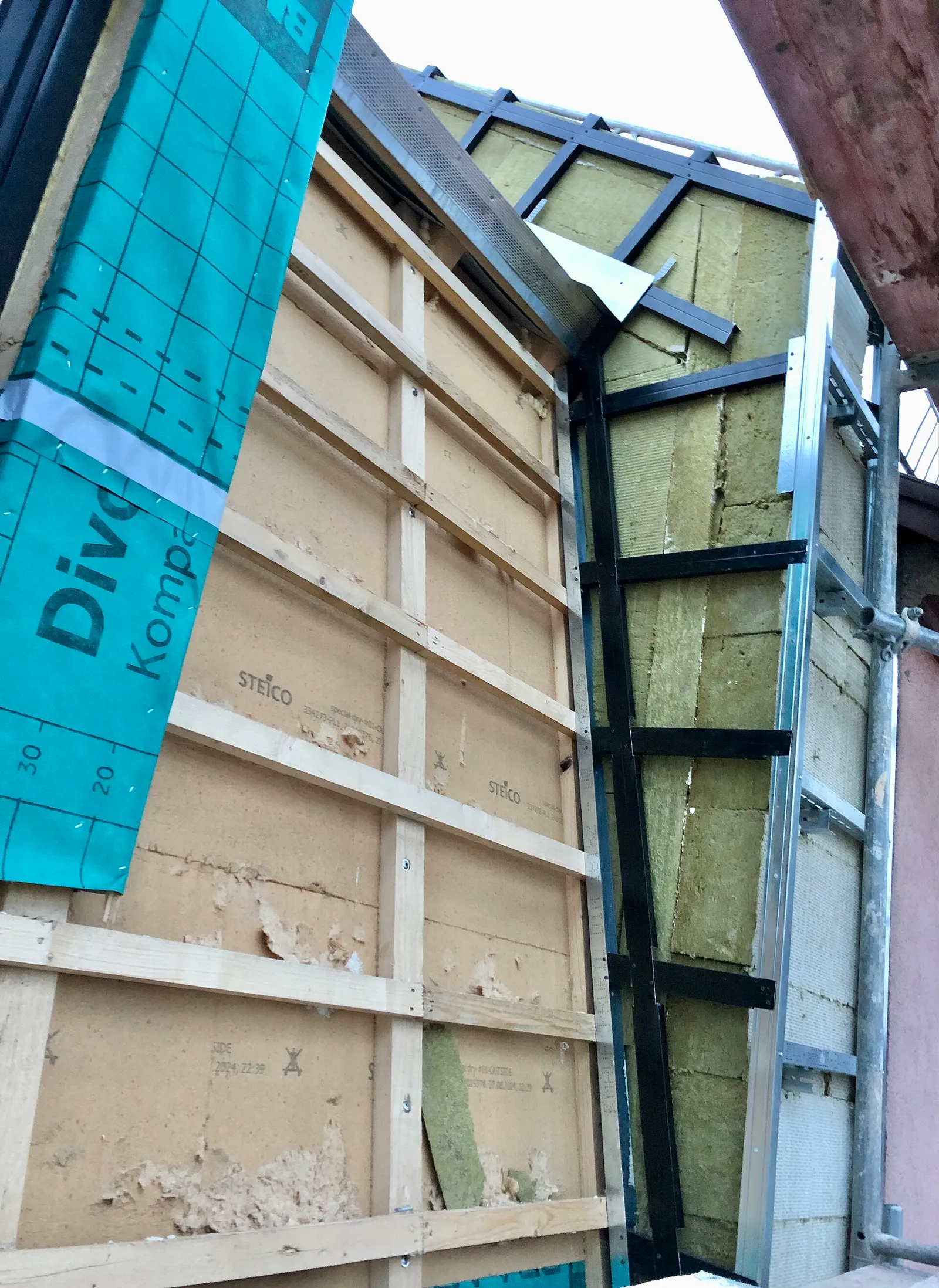 Pignon en cours d'isolation avec laine de roche sur ossature et membrane pare-pluie bleue