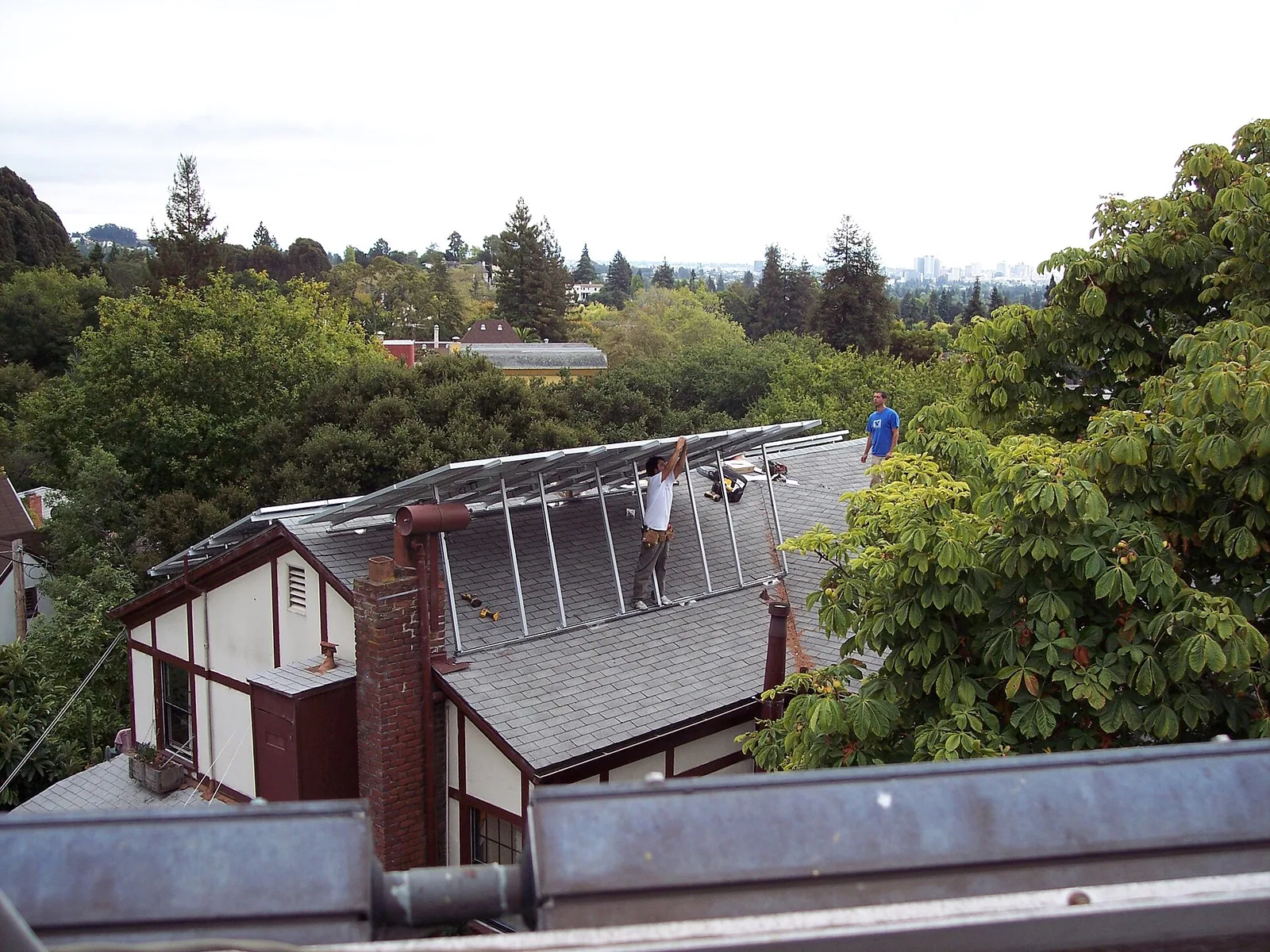 Installateurs fixant des rails de montage en aluminium sur le toit en bardeaux d'une maison avant la pose des panneaux solaires