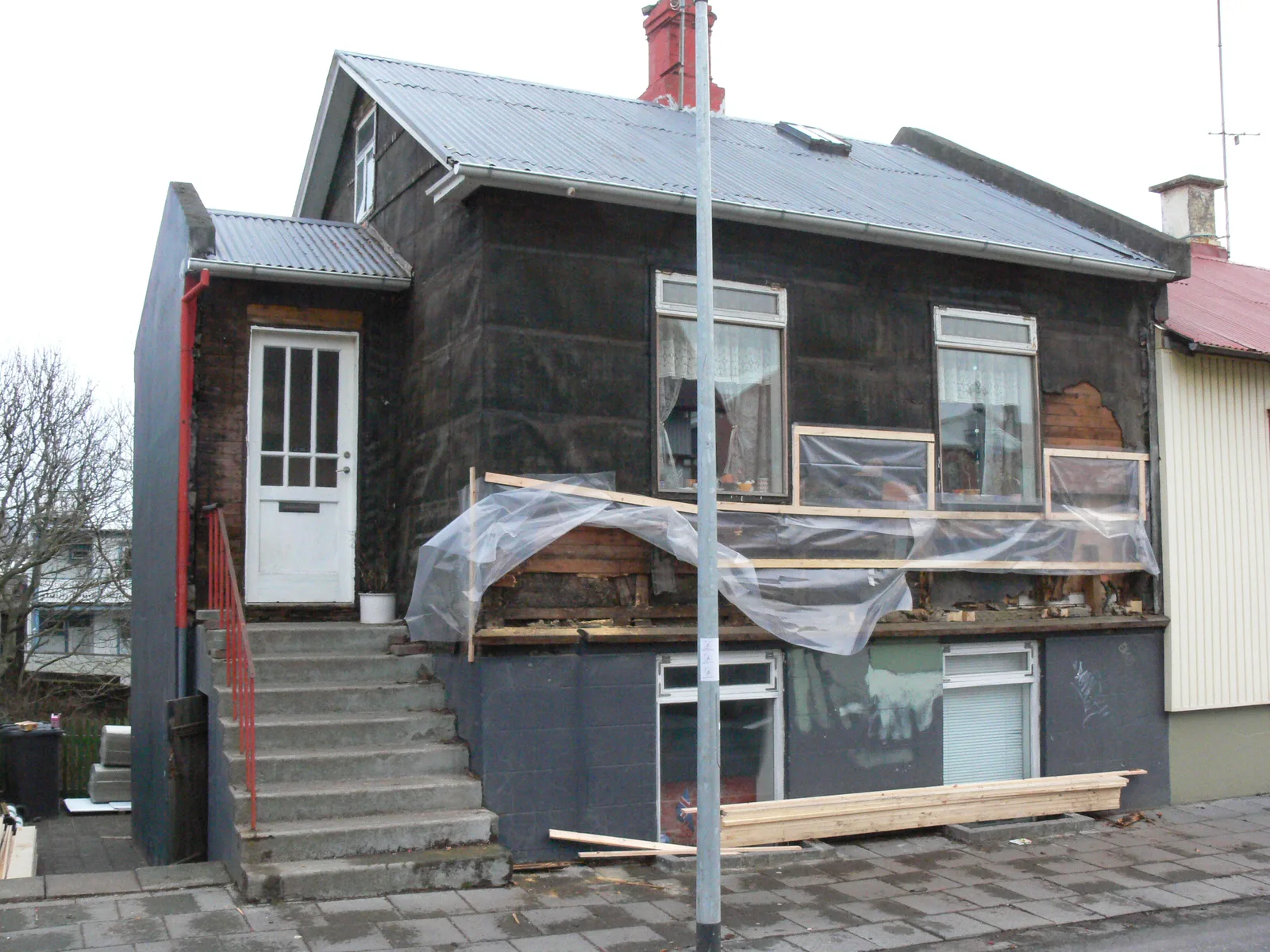 Façade d'une maison individuelle dont le bardage est déposé pour être rénové