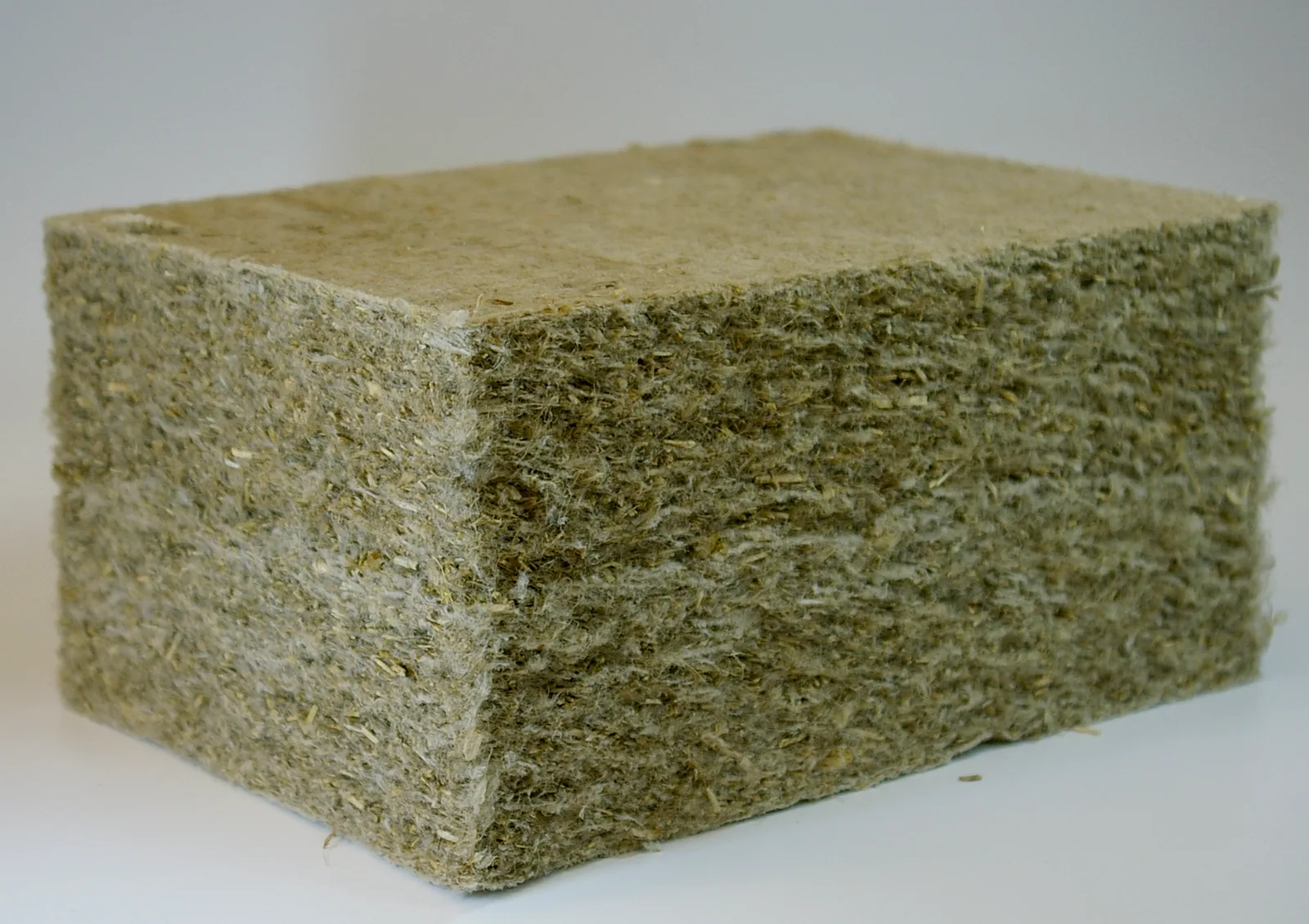 Bloc d'isolant en fibres de chanvre de couleur vert-gris, découpé pour montrer sa texture fibreuse dense