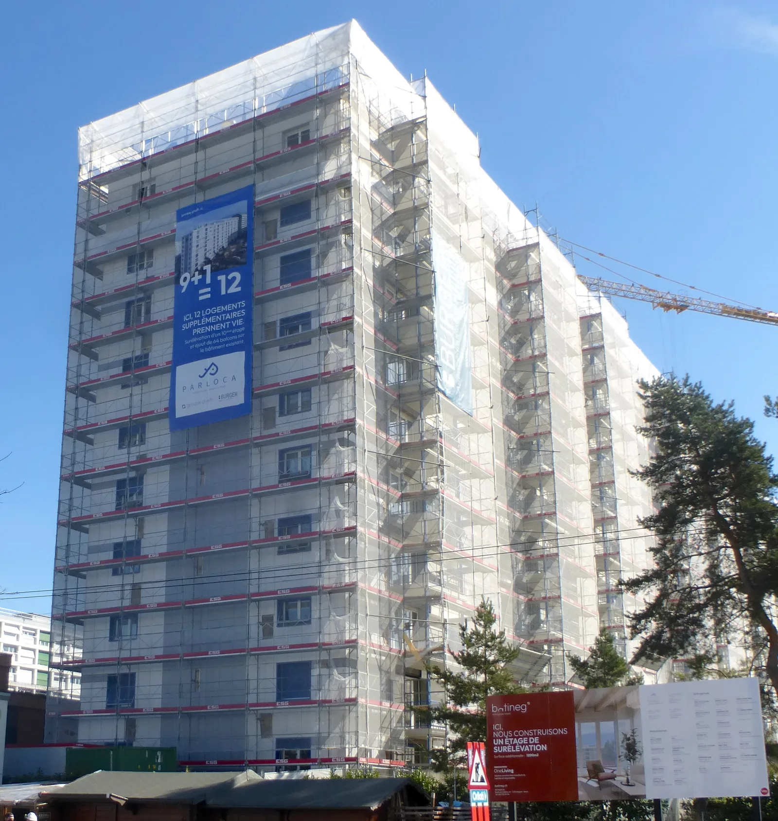 Tour d'habitation de dix étages recouverte d'échafaudages et de bâches pendant un chantier de rénovation