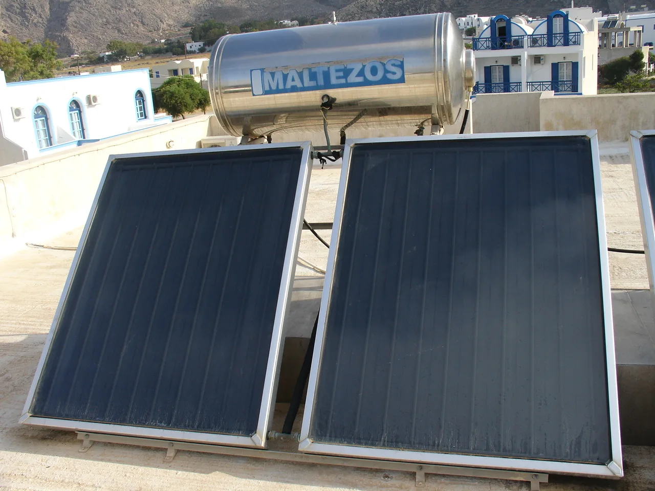 Deux capteurs solaires plans et leur ballon d'eau chaude en inox installés sur un toit-terrasse