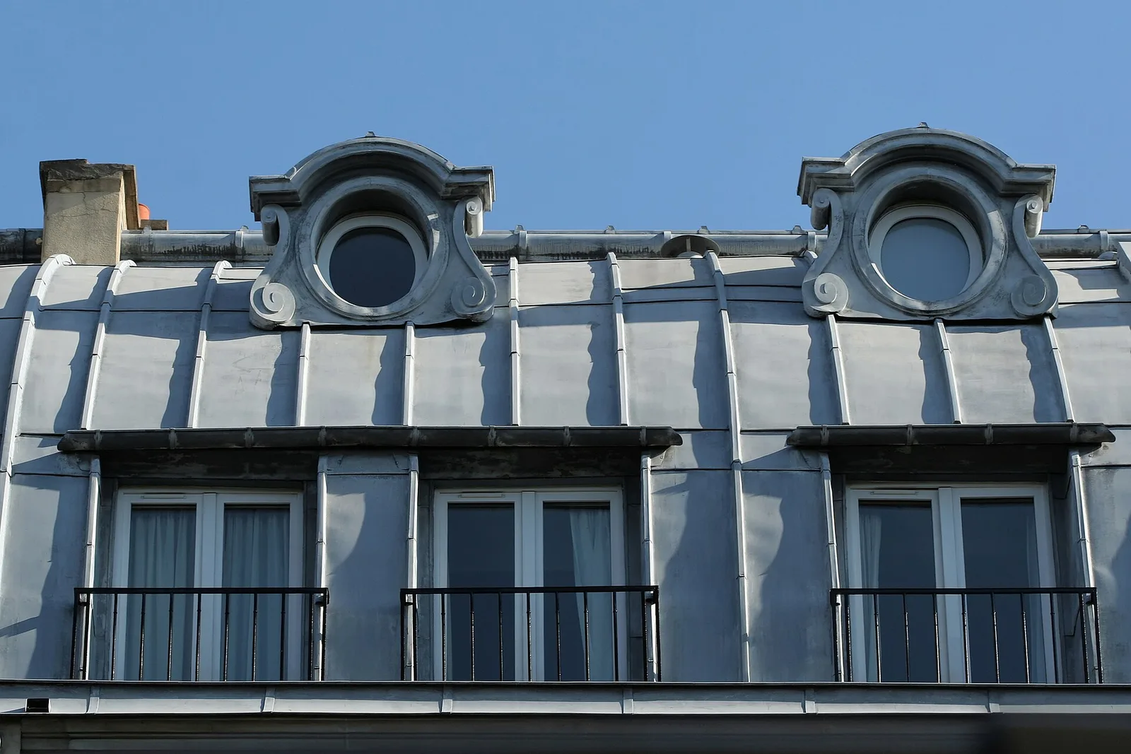 Toiture en zinc d'un immeuble parisien du boulevard Saint-Michel avec lucarnes en œil-de-bœuf et fenêtres de chambres sous combles