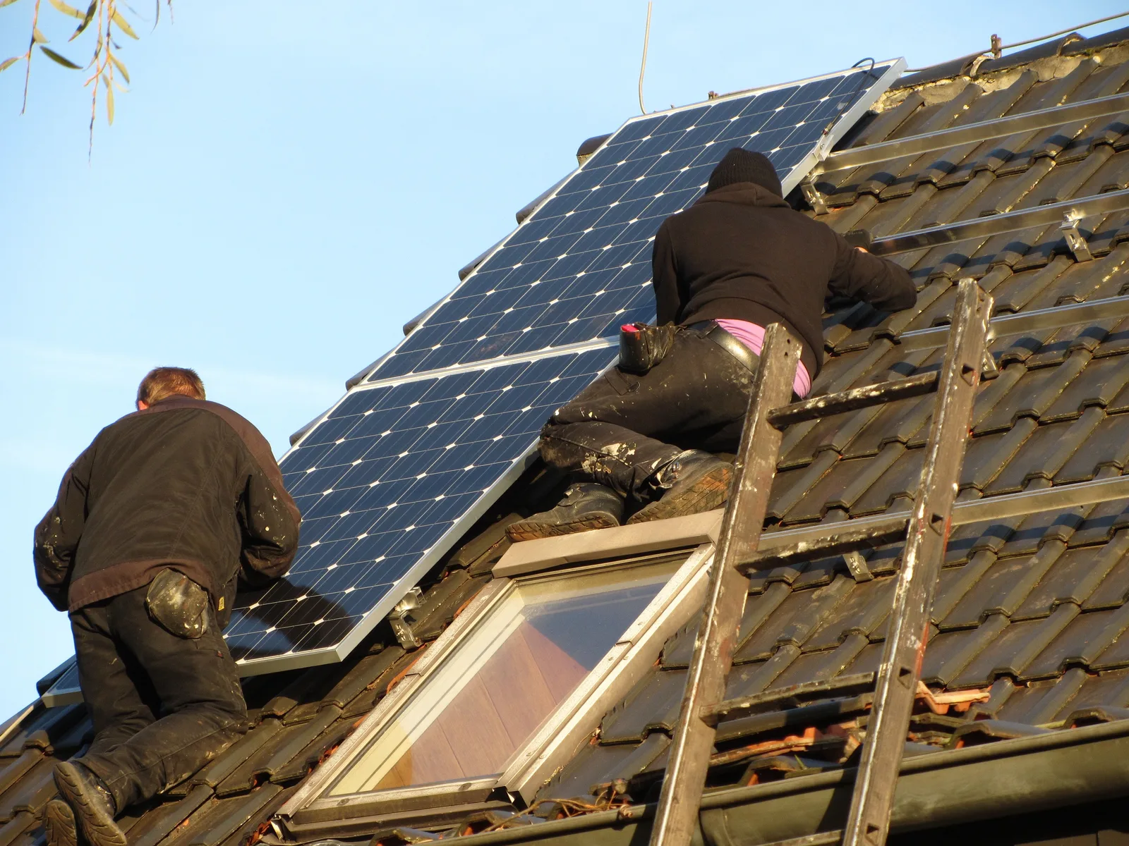 Technicien installant des panneaux solaires sur un toit, travaux éligibles à la TVA réduite sous conditions de puissance